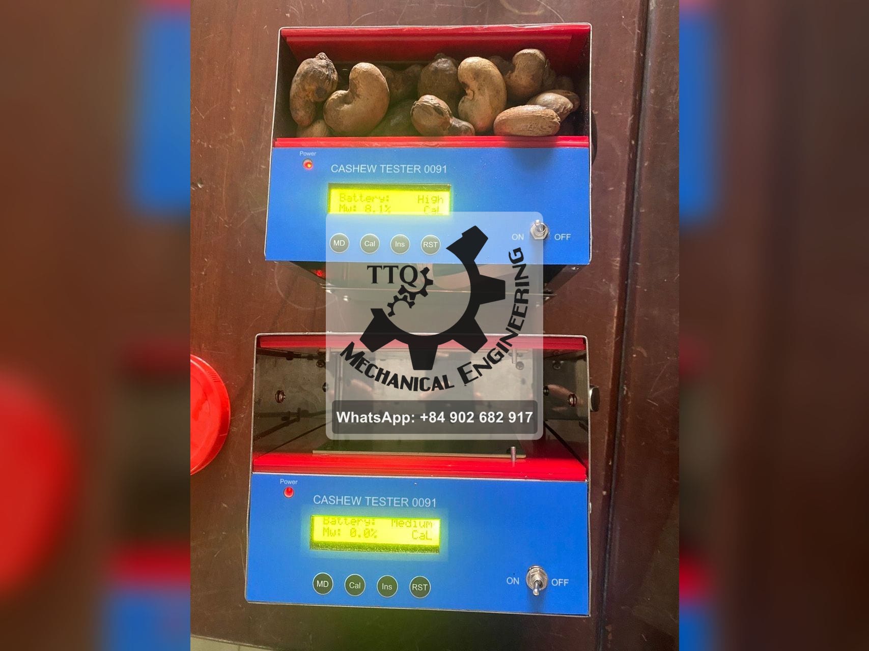 Two CASHEW TESTER 0091 moisture meters, the upper cell loaded with raw nuts and reading 8.1%