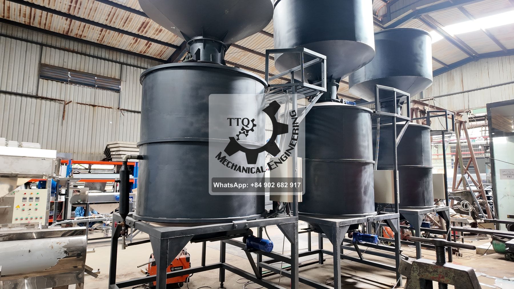 Cashew steaming vessels arranged in line, each fed from the hopper above