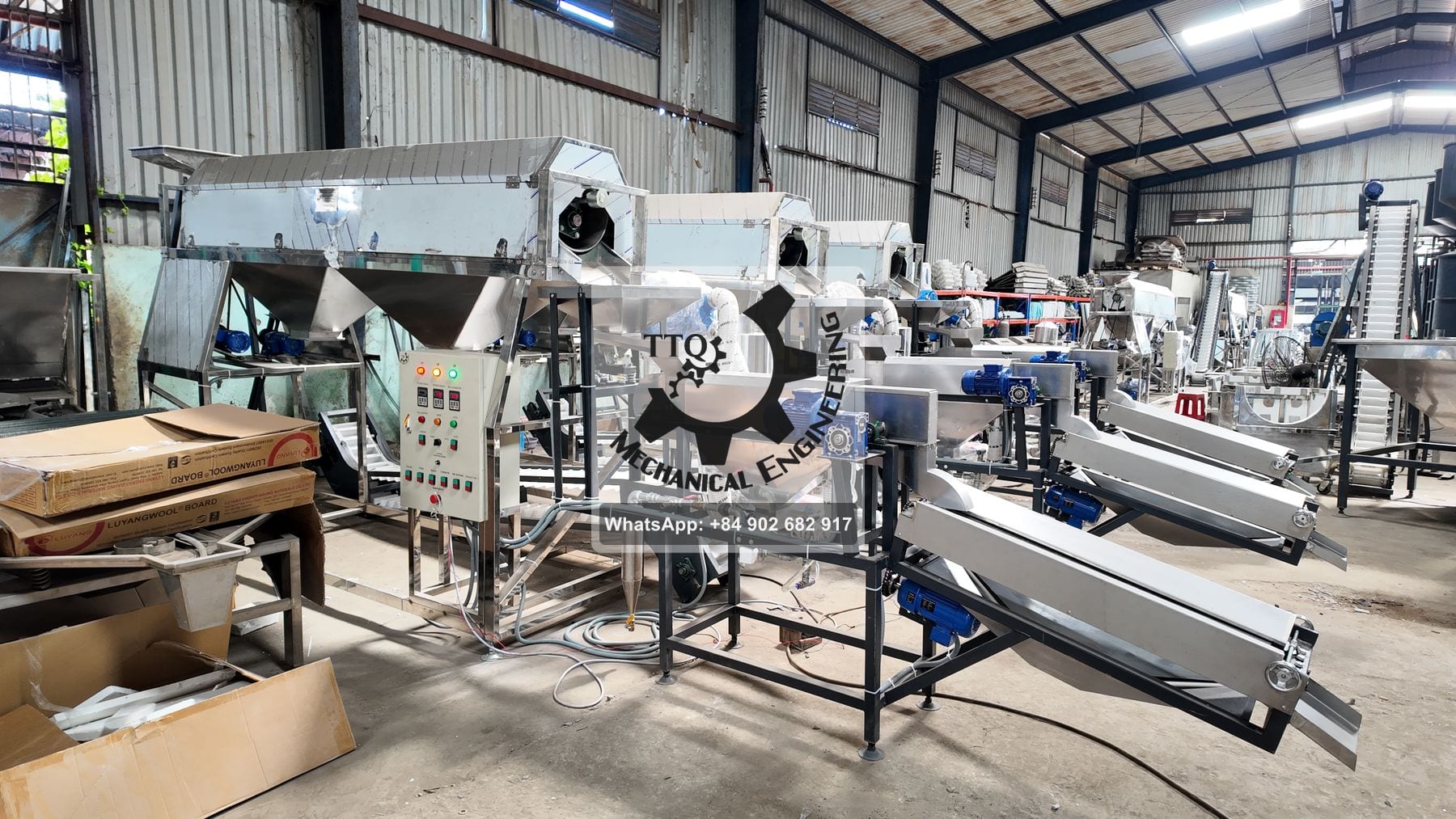 A row of automatic TTQ peeling machines with hoppers, screw conveyors and incline belts