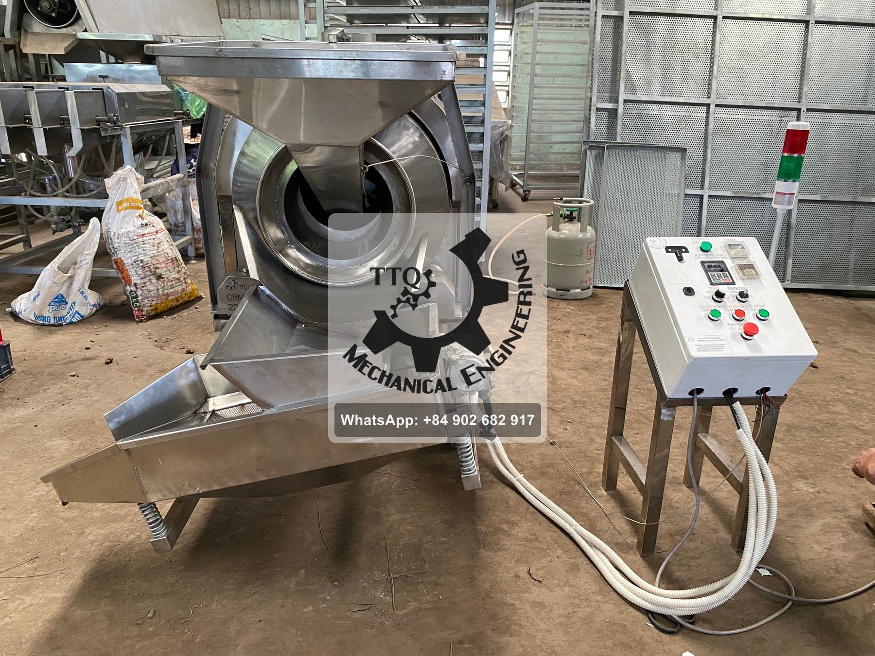 A TTQ drum roaster with feed hopper, discharge chute onto a vibrating tray, and a separate control pedestal